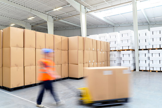 warehouse shipping // Lagerist mit Hubwagen in einem Warenhaus