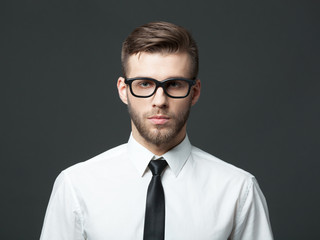 Portrait of handsome young businessman on dark background.