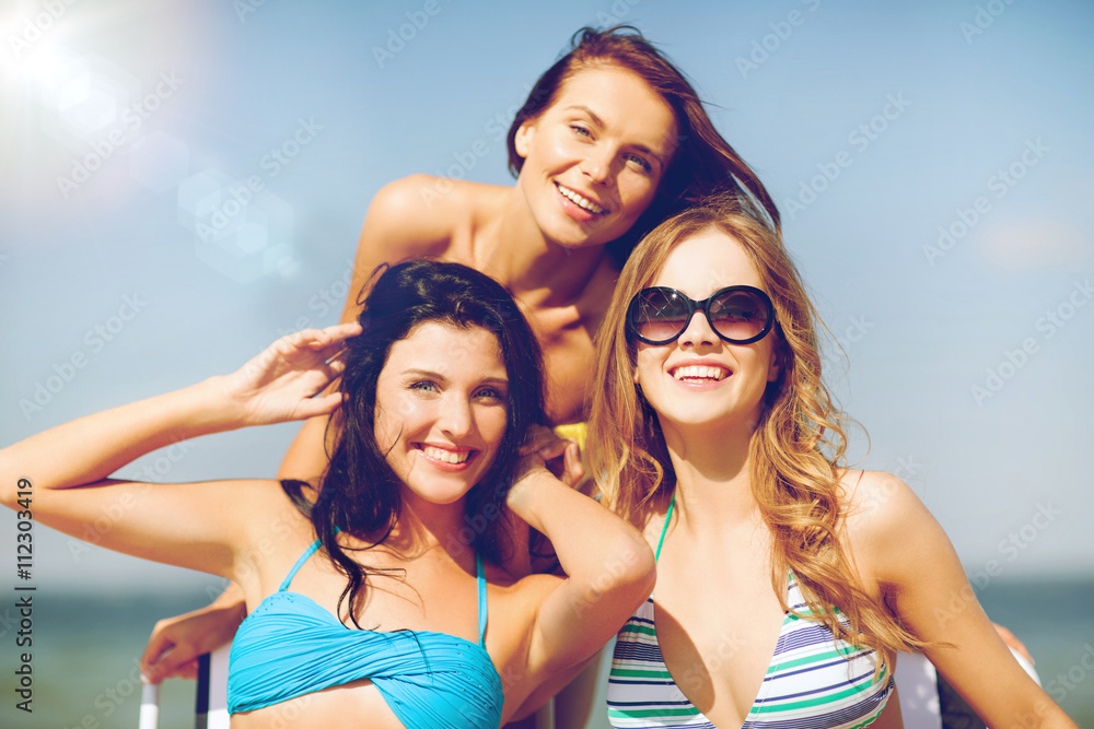 Poster girls sunbathing on the beach chairs