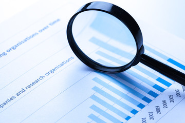 Fototapeta premium financial documents with magnifying glass over them