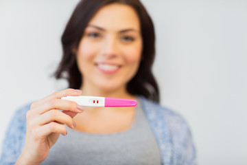 close up of happy woman with home pregnancy test