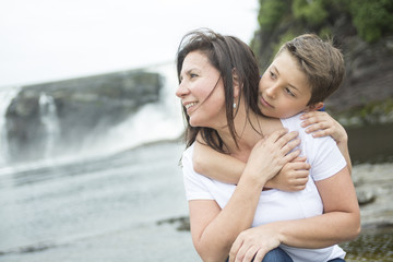 mother and son playing in front of a waterfall