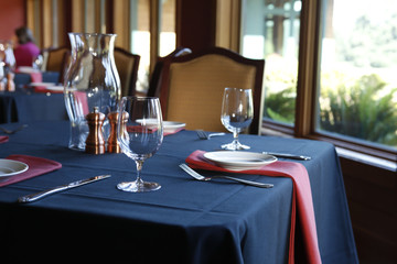 Table setting in  a restaurant with a blue tablecloth and red na