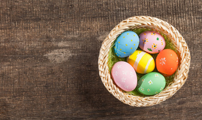 Easter eggs in nest on color wooden background