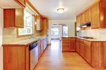 Sunny brown kitchen interior with hardwood floor and white ceili