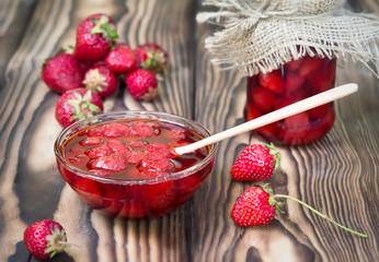 Strawberry jam marmalade in glass bowl on wooden background.