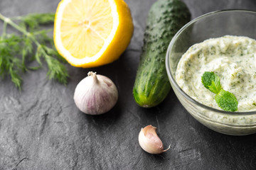 Tzatziki  on the black stone table with ingredients horizontal