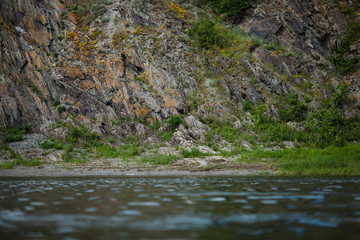 Naklejka na ściany i meble Rocks with orange lichen, scenic view from river
