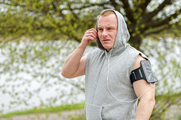 Fit man jogger listening music by earphones.