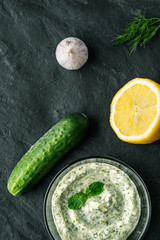 Tzatziki  on the dark stone table with ingredients