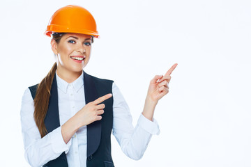 Woman builder in helmet points finger at copy space