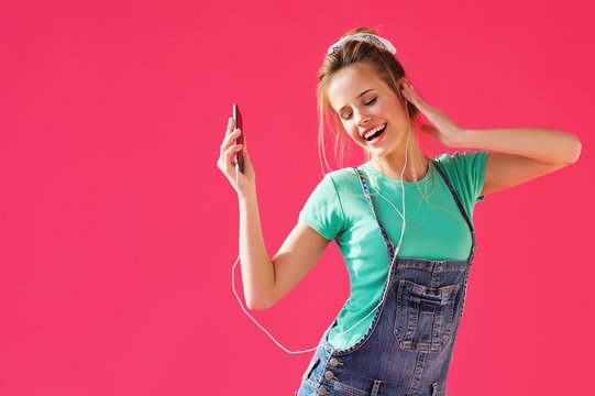 Positive young woman listening to music from her phone and dancing