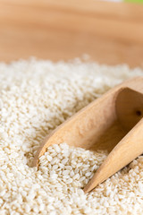 Macro closeup wooden spoon in the pile of sesame