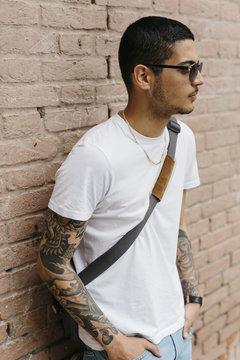 Young man leaning against a brick wall