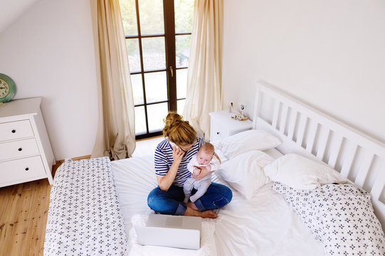 Mother with baby at home working with laptop
