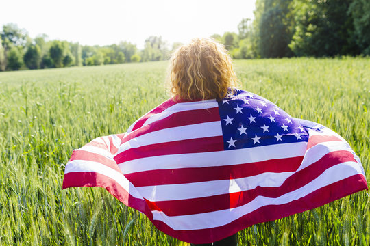 Back view of woman with American Flag in nature