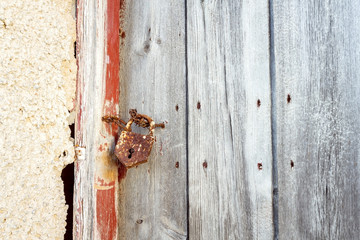 Old rusty padlock, wooden door and old grungy concrete wall, vintage background