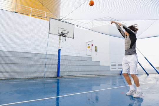 Young man playing basketball on a deck of a cruise ship