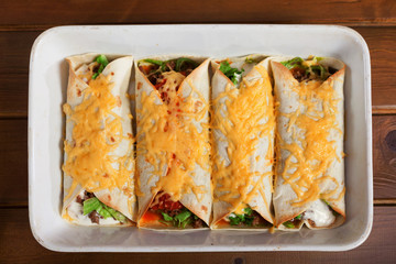 Mexican burittos in a baking dish. Shot from above over wooden background