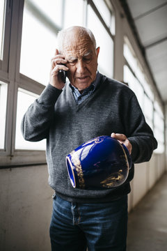 Elderly man reviewing the ceramic vase, talking on the phone