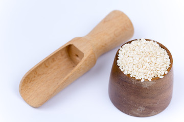 Wooden measuring spoon with bowl full of sesame
