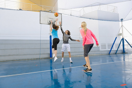 Three people playing basketball on a deck of a cruise ship
