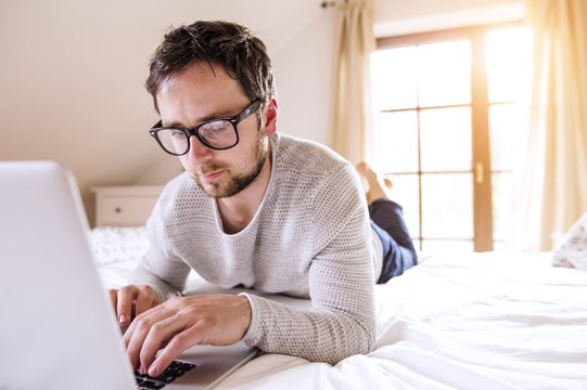 Man lying on bed using laptop