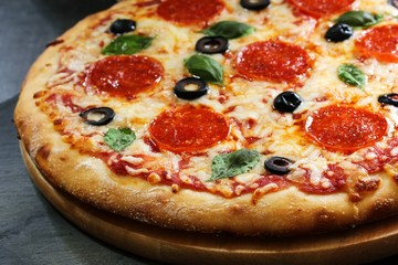 Homemade Pizza with basil black olives and peperoni, close up, selective focus