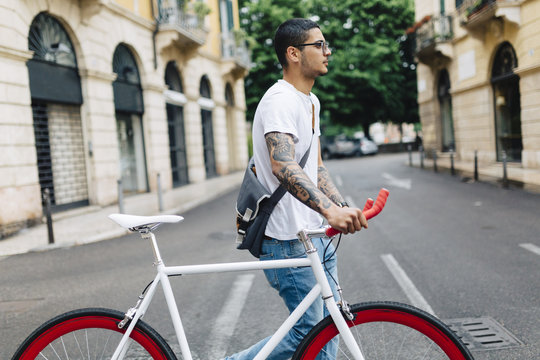 Young man walking with a bicycle in the city
