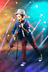 Little boy singing with microphone on laser rays background