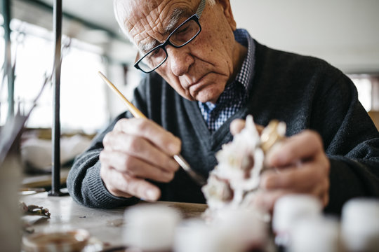 Senior man decorating ceramic in his spare time