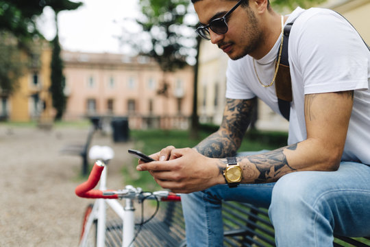 Young man sitting on bench looking at cell phone