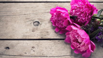 Bunch of pink peonies flowers on aged wooden background.