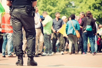 Armed police officer standing guard at a protest mars in a city