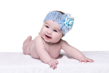 cute baby girl with blue bow flower on her head. child with big blue eyes looking away and smiling. portrait of baby girl on white background