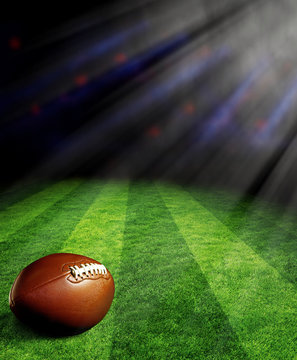 American football on green field with spotlights