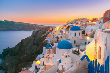 Malerische Aussicht, Altstadt von Oia oder Ia auf der Insel Santorini, weiße Häuser und Kirche mit blauen Kuppeln bei Sonnenuntergang, Griechenland