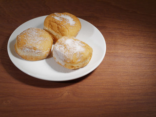 Plate with donuts on a wooden table.