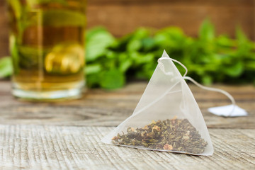 Tea bag on background of mint and and cup of tea