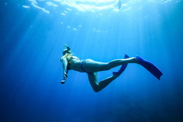 Obraz na płótnie Canvas Underwater woman snorkeling in blue tropical sea