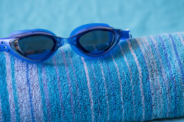 Blue swimming goggles on beach towel
