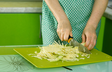 women's hands cut the cabbage on green chalkboard