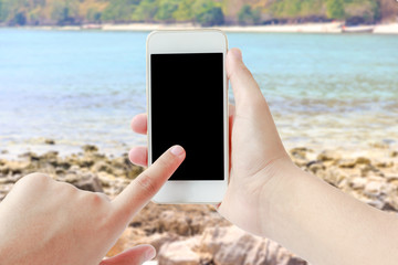 Female hand touching smartphone while on the beach
