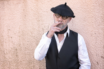 Portrait of a mature man wearing tradition french clothing and smoking a cigarette. Taken with copy space. 
