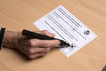 Obraz premium Completing a postal ballot paper with a cross in a box to stay in the European Union.
