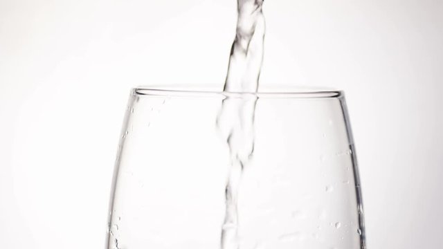 4K Stream of water pouring into a glass, in slow motion