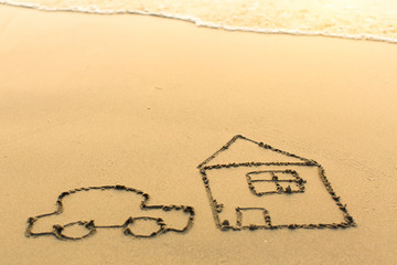 Car and the house drawn on the sand of a beach with the soft wave.
