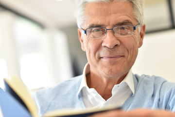 Senior man relaxing at home with book