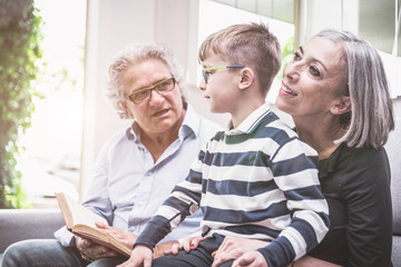 Grandparents spending time with grandson. reading him story in t