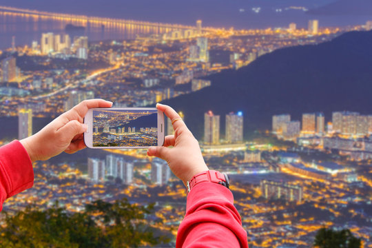 Smartphone photographing Top view of Georgetown, capital of Penang Island, Malaysia from top of Penang hill.